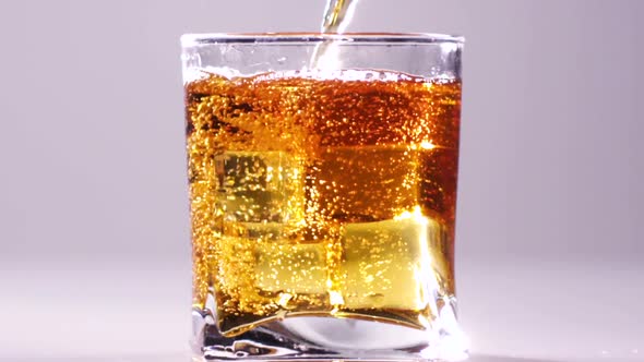 Pouring Whiskey in Glass with Ice Isolated on White. Slow Motion. End Process