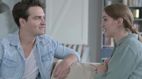 Cheerful Couple Smiling and Talking Sitting on Sofa