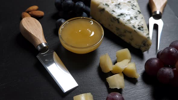 Sliced Cheese, Nuts, Grape, Honey and Knife on Shale Platter