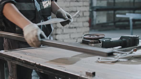 Young Man Brings Metal Long Detail and Instruction to the Table and Reading the Instruction