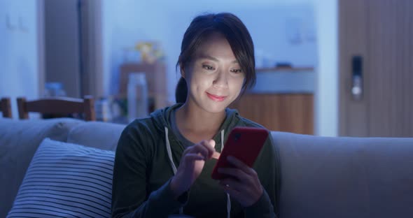 Woman use of smart phone sit on sofa at home in evening