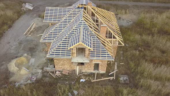 Aerial view of a house under construction works. Unfinished brick building with wooden frame for