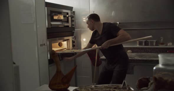 Man putting pizzas into oven