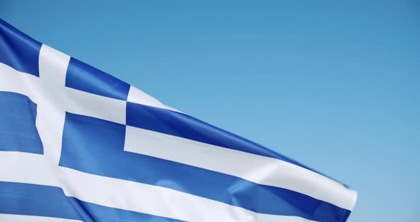 Close Up Crop of Greek Flag Flying on the Calm Wind Flutters with Bright Blue Sky in Background