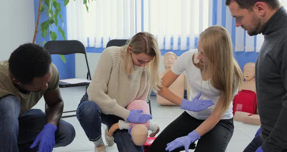 People Learning How to Safe a Life When the Baby is Choked Sitting Together with Instructor During