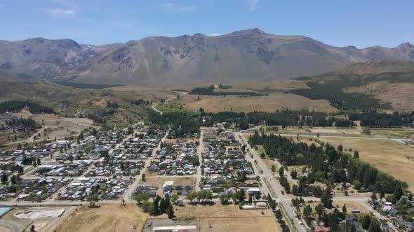 Dolly in flying over Esquel city surrounded by woods with mountains in background, Patagonia Argenti