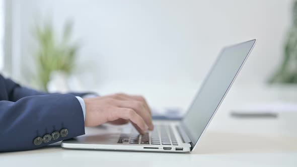 Side View of Businessman Typing on Laptop