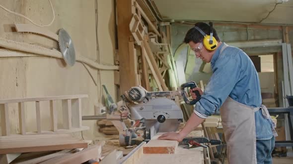 Carpenter Working with Bandsaw in Workshop alt