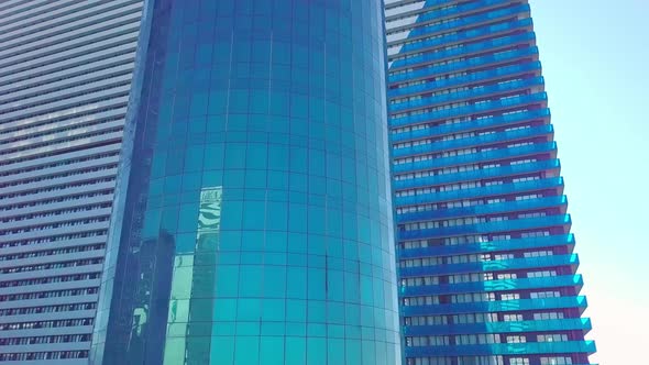 shot of reflections of sun, clouds and sky on glass windows of city skyscraper.