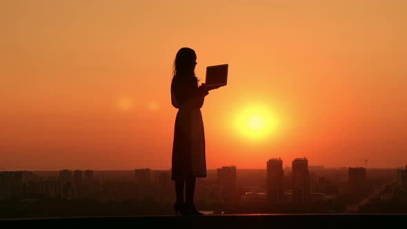 Woman with Computer Outdoors Cityscape at Sunrise