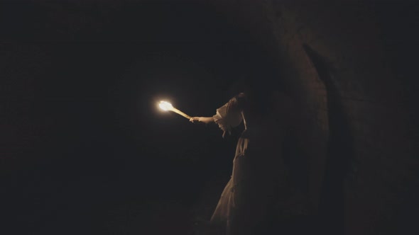 Woman With a Torch Running through XVIII century Dungeon