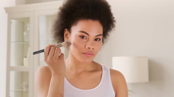 African american woman make up beauty routine. Applying powder with a brush