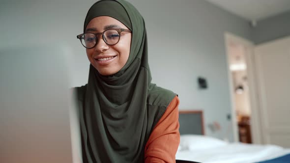 Muslim handsome woman wearing eyeglasses talking by video call on laptop
