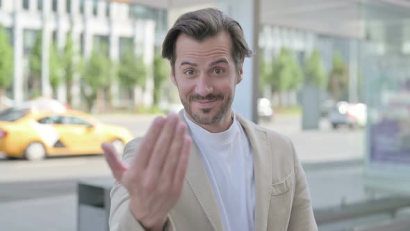 Young Man Pointing at the Camera and Inviting Outdoor