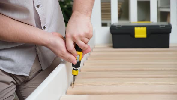 The Furniture Assembler Assembles the Bed Twists the Screws on the Wooden Slats