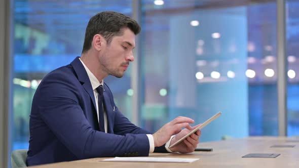 Serious Businessman Using Tablet at Work