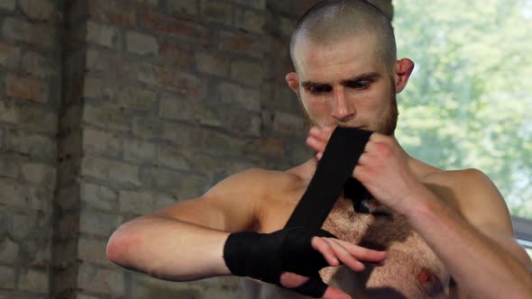 Bearded Male Boxer Wrapping His Knuckles Before Fighting