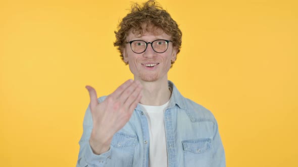 Redhead Young Man Pointing and Inviting, Yellow Background 