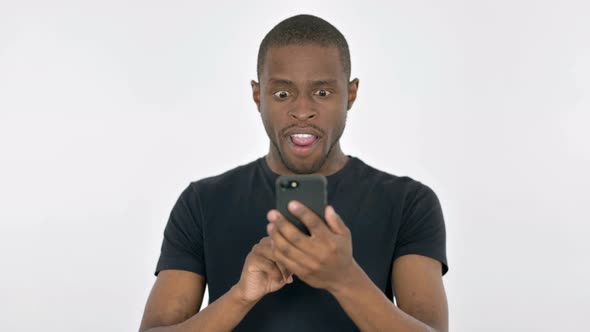 Young African Man Celebrating on Smartphone on White Background