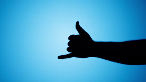 Shadow of Hawaiian Shaka Greeting Gesture Isolated on Blue Neon Background