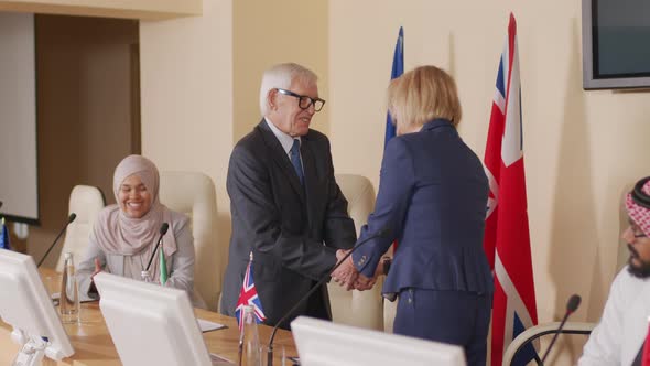 Two Smiling Politicians Shaking Hands at Press Conference