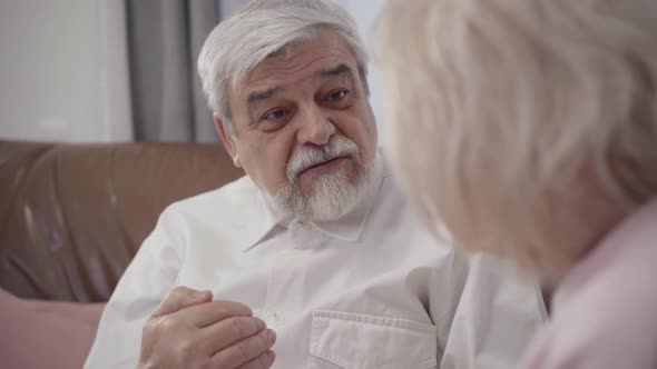 Close-up Face of Handsome Old Caucasian Man Talking with Unrecognizable Blond Woman, Smiling Husband