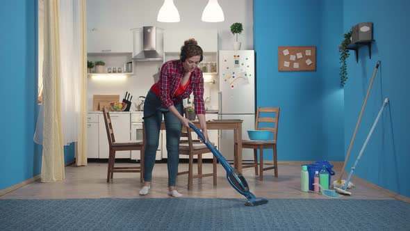 Housewife Cleans the Carpet with a Vacuum Cleaner.