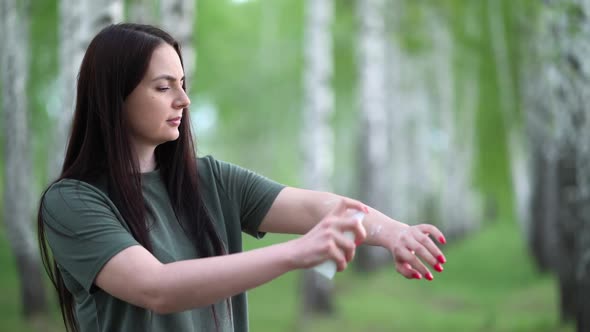 Young Woman in a Birch Grove Puts a Mosquito Repellent on Her Skin.