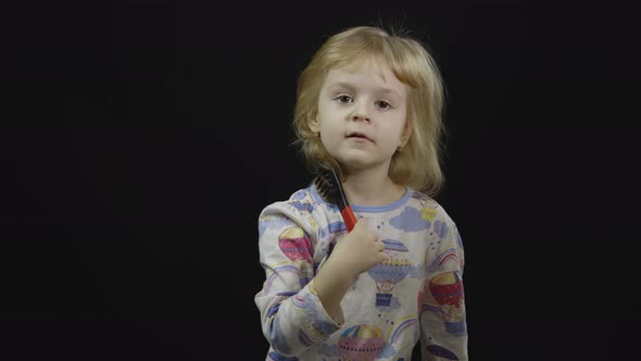 Little Baby Girl in Pajama with Funny Headdress Is Combing