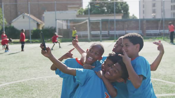 Soccer kids in blue taking a selfie and laughing in a sunny day