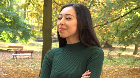 A Young Asian Woman Looks Around a Park and Smiles on A Sunny Day