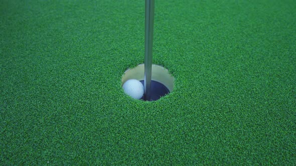Close up golf ball in hole on grass in golf club, simulation court sport equipment