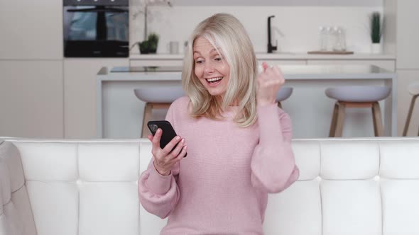 Excited Happy Mature Old 60s Woman Winner Holding Smartphone Using Mobile App Winning Online Lottery