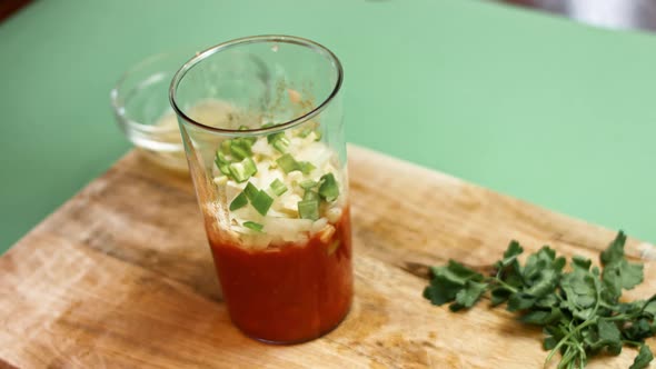 Pouring diced tomatoes from an open can into hand blender glass. Process of making salsa