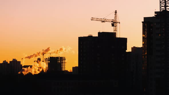 Cranes Working on Construction Site Residential Constructors are Working at Sunrise or Sunset