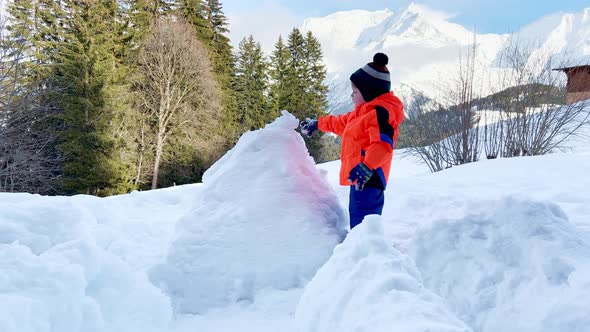 Little Boy Play in the Snow Fortress Over Mountain on Back