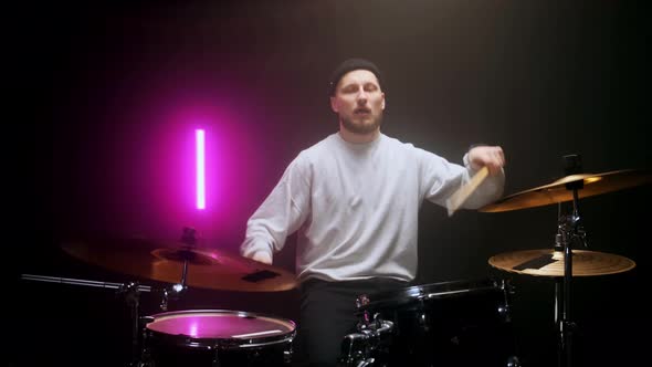 Drummer Playing the Drum Set in a Dark Room on a Black Background