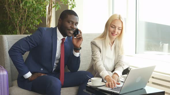 Mixed-race Business Couple Waits for Taxi in Airport.