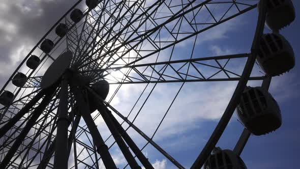 Ferris Wheel and Sun in Sky with Clouds