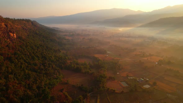 Aerial view over villages and barren fields in countryside during sunrise