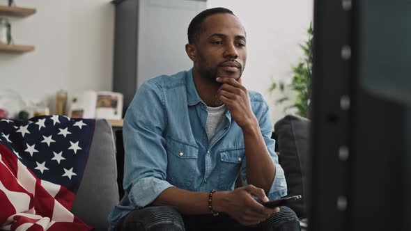 Handheld video of satisfied black man watching TV. Shot with RED helium camera in 8K.