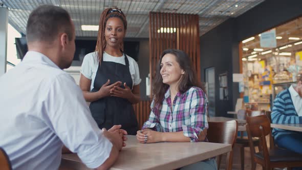 Young Couple Placing Order in Restaurant or Bistro with Waiter