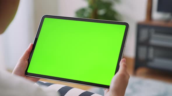 woman holding in hands a digital tablet with green screen for internet online.