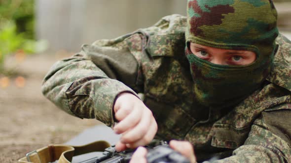 Closeup of a Masked Soldier Preparing to Fire and Pointing the Machine Gun Towards the Camera