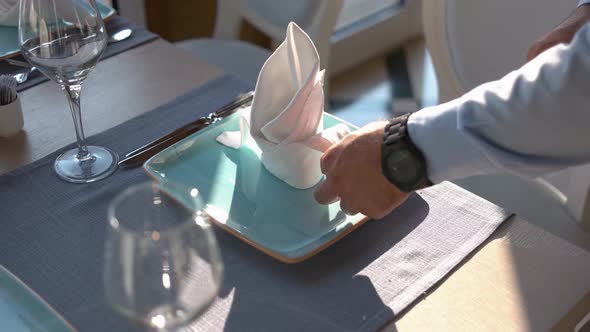 Waiter Puts Napkin and Forks on Table in Restaurant.