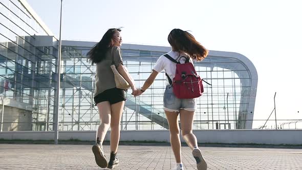 Two Young Modern Asian Women which Running Near the Airport Building