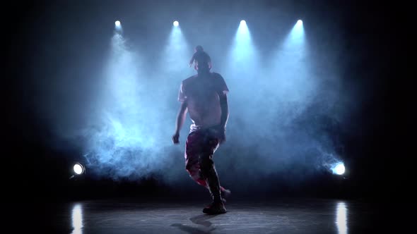 Man Enjoying Hip Hop Moves in Dark Studio with Smoke and Lighting.