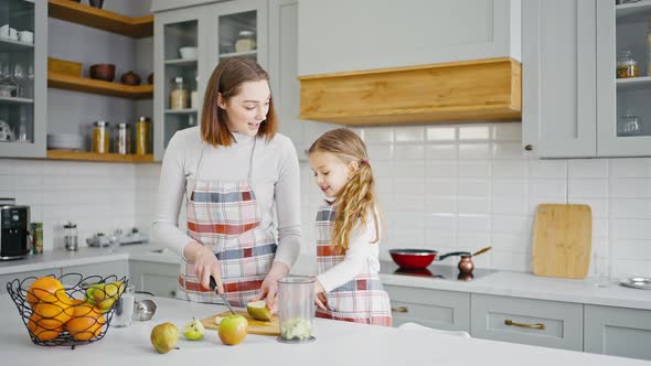 Cute Girl Helping Her Mother at Kitchen Eating Cut Apple and Laughing