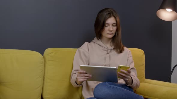 Attractive Girl Chatting and Messaging Sitting on Sofa in Stylish Living Room