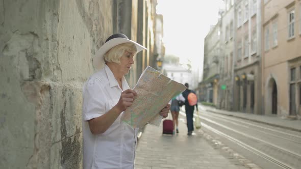 Senior Female Tourist Exploring Town with a Map in Hands. Looking for the Route